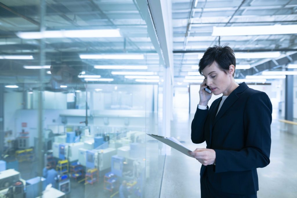 business woman on phone overlooking factory